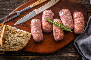Photo of italian sausage salsiccia on cutting board on wooden table. Top view.