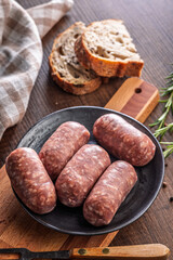 Photo of italian sausage salsiccia on plate on wooden table.