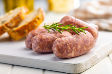 Photo of italian sausage salsiccia on cutting board on white table.