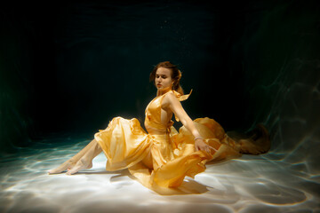 An Ethereal Underwater Dance Taking Place in a Beautiful Yellow Gown and Flowing Elegantly