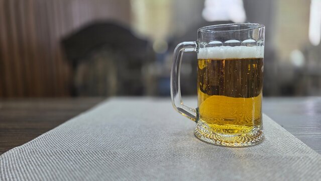 Refreshing mug of beer on a table in a cozy pub setting. Horizontal banner. Copy space. Free space for text. International beer day