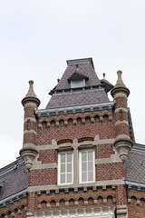 Close-up of a beautiful red-brick facade with detailed stone framing and conical corner turrets in...