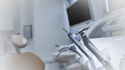 Horizontal close-up of professional dental handpieces on a white control panel of dentist chair. Includes ultrasonic scaler, polishing brush and air syringe. Concept of modern dentistry, hygiene and