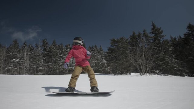 4K video of a woman snowboarding down a cold winter mountain on a sunny snowy day at Killington, Vermont, New England, USA. Thrill and excitement. 