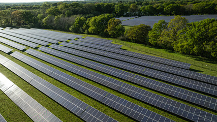 An expansive solar panel farm nestles in the green, serene landscape by a sparkling lake.