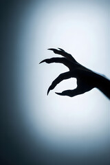 Monster hand with long claws reaching out of dark fog. Scary gesture expressing fear or horror for Halloween vertical concept with copy space.