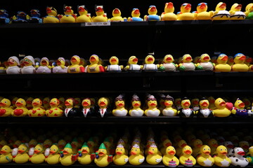 Colourful display of rubber ducks arranged neatly on store shelves, each designed with different costumes and expression