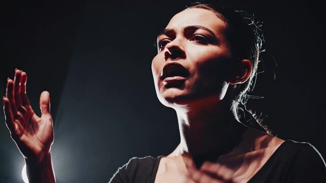 Passionate actress performing a monologue on a dark theatrical stage. Intense and emotional close up portrait of her powerful performance