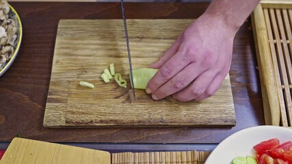 Experience the crisp sounds of food preparation as a chef expertly dices a fresh green cucumber on a rustic wooden cutting board, ideal for healthy eating concepts.