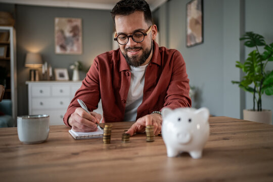Man calculating savings with coins and piggy bank