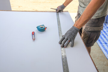 Man is measuring a piece of wood with a ruler