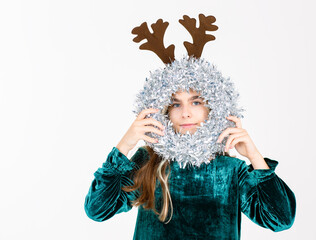 Cheerful teen girl in velvet dress brown reindeer antlers festive ornaments, celebrating holiday season on white background.