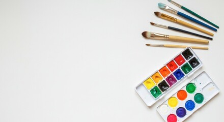 Colorful art supplies and paintbrushes on white canvas background for creative design
