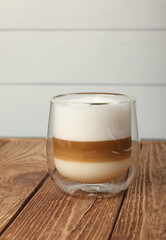 Latte macchiato coffee resting on a wooden table with a white background