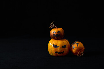Cute Halloween pumpkins with jack-o'-lantern faces arranged in a playful group on a black background