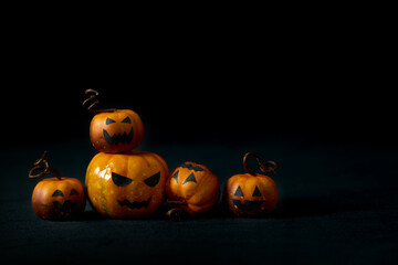 Cute Halloween pumpkins with jack-o'-lantern faces arranged in a playful group on a black background