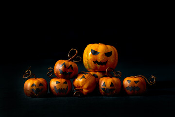 Cute Halloween pumpkins with jack-o'-lantern faces arranged in a playful group on a black background