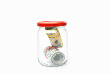 Saving money in a jar with dollar and euro notes for future financial goals