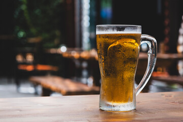 50 cl pint of beer served on wooden surface. Cold beer glass on wooden table. Refreshing golden beer in glass on wooden table. Full glass of lager beer on wooden table.