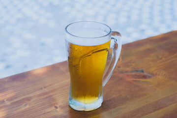 50 cl pint of beer served on wooden surface. Cold beer glass on wooden table. Refreshing golden beer in glass on wooden table. Full glass of lager beer on wooden table.