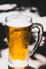 50 cl pint of beer served on wooden surface. Cold beer glass on wooden table. Refreshing golden beer in glass on wooden table. Full glass of lager beer on wooden table.