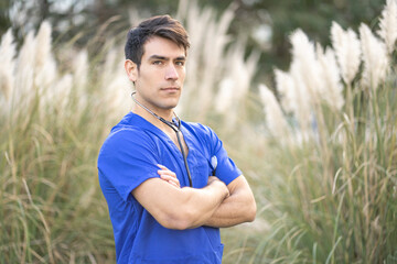 Fototapeta premium Handsome male medical professional standing in front of tall natural grass