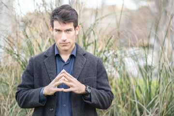 Man in a long coat making the steeple gesture, symbolizing power and focus