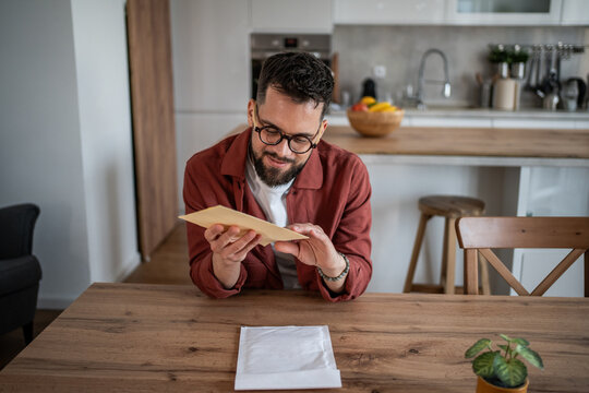 Man opening and reading paper mail at home kitchen table