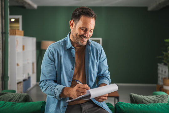 Man smiling checking list clipboard working from home office - Powered by Adobe