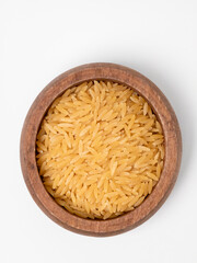 Dry orzo pasta in a round wooden bowl isolated on a white background