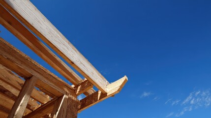 The image presents a low-angle perspective of a wooden structure under construction, its weathered beams and supports juxtaposed with a bright, cloudless, azure sky.