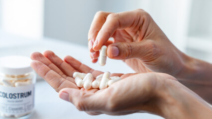 Person holding colostrum capsules, dietary supplement for immunity and gut health, natural wellness product, probiotic support, daily nutrition routine, immune system booster