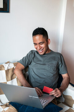 Latino making secure online payment with laptop and bank card