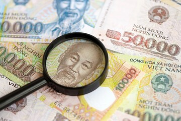 Vietnamese dong currency money bills and magnifying glass close up. The concept of financial monitoring and taxation