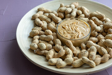 Close-Up of Peanuts on a Wooden Plate with a Bowl of Peanut Butter in the Center
