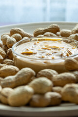 Close-Up of Peanuts on a Wooden Plate with a Bowl of Peanut Butter in the Center
