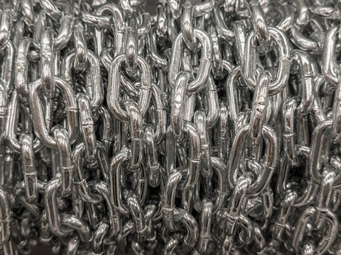 Close-up of coiled heavy-duty steel chain links, vital for construction rigging, industrial lifting, cargo securing, and binding in shipping and manufacturing.