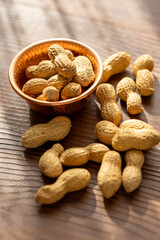 Close-Up of Raw Peanuts in a Copper Cup on a Brown Wooden Table
