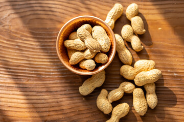 Close-Up of Raw Peanuts in a Copper Cup on a Brown Wooden Table
