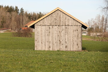 Obraz premium A small, old wooden building sits in a grassy field