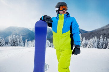 Snowboarder Of Man At Ski Resort On The Background Blue Sky,  Hold Snowboard. Wearing Ski Glasses