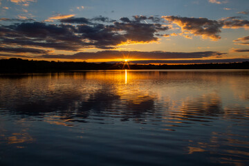 Colourful cloudy sunset reflected in the still surface of a lake, Ravensthorpe reservoir, Northamptonshire, England