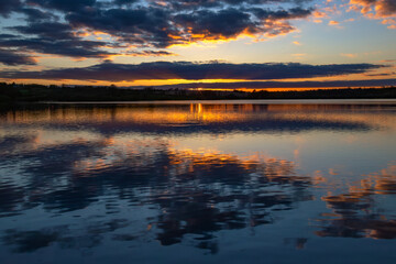 Colourful cloudy sunset reflected in the still surface of a lake, Ravensthorpe reservoir, Northamptonshire, England