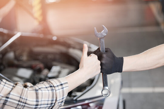 Closeup woman thumb up hand and auto mechanic hold wrench in car repair garage service