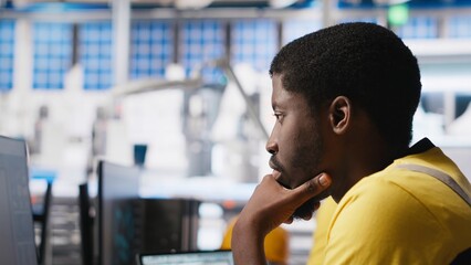 Black engineer works on solar software settings in automated factory, optimizing the production...