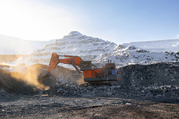 Excavator mining in open-pit coal mine during winter