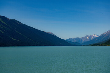 Obraz premium Scenic lake surrounded by mountains under a clear blue sky on a sunny day.