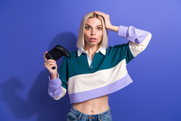 Young stylish woman holding a gaming controller with a surprised expression in a casual colorful...