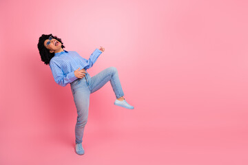 Energetic young woman joyfully posing against vibrant pink background, wearing stylish casual clothes and sunglasses