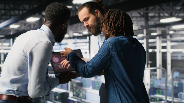 Worried workers trying to fix hacked infrastructure systems. Panicked engineers in data center react to ransomware warning on laptop screen, scrambling to launch emergency response protocol